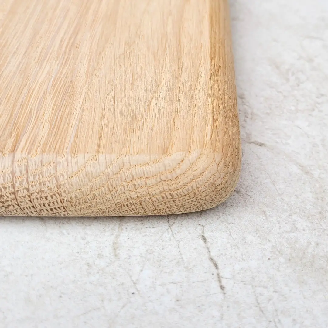 Zaokrąglony róg gładkiej deski do krojenia surowo wykończona, naturalna deska dębowa bez impregnacji, surowy blok kuchenny z polskiego drewna, ekologiczna deska do serwowania o szlifowanej powierzchni, nielakierowana twarda deska z zaokrąglonymi krawędziami, produkt handmade z certyfikowanego drewna, smooth rounded rough finished cutting board corner, unfinished solid wood chopping board, natural oak board with sanded edges, raw wood kitchen block with rounded corners, eco-friendly untreated wooden server, handcrafted raw oak board from Poland, professional grade unfinished wood cutting surface